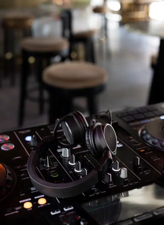 Auriculares de DJ sobre una mesa de mezclas en un entorno de bar o local elegante