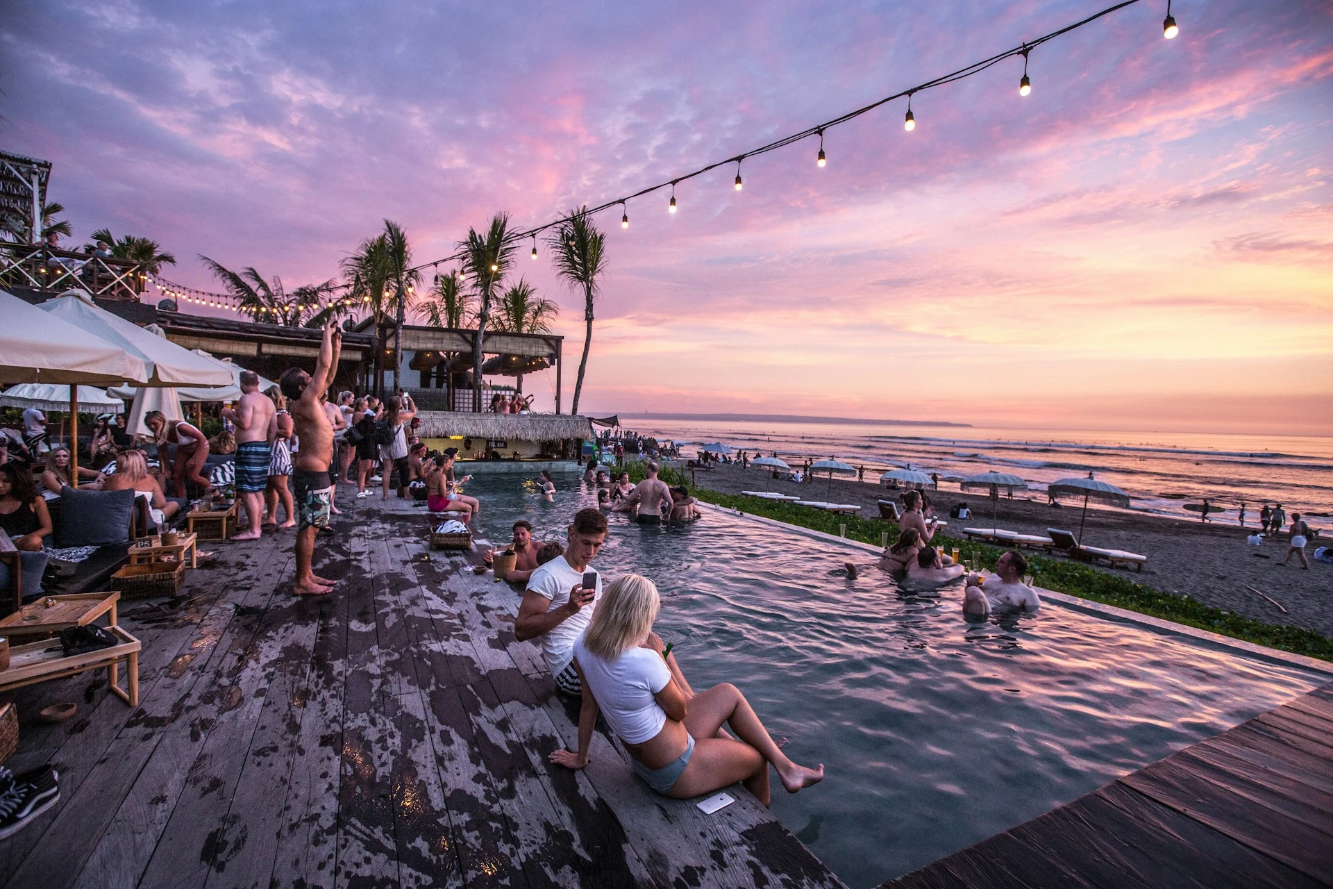 Panorámica de una fiesta en la piscina con vistas a la playa al atardecer